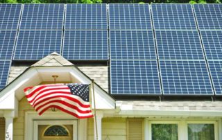 Evergreen Residential Solar array on a house rooftop with an American flag flying in the front yard.