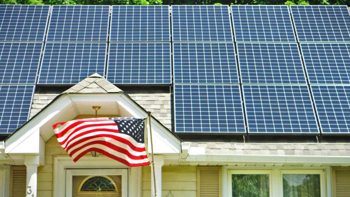 Evergreen Residential Solar array on a house rooftop with an American flag flying in the front yard.