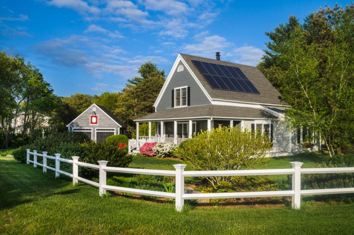 Photo shows a home with white trim and solar panels installed on rooftop