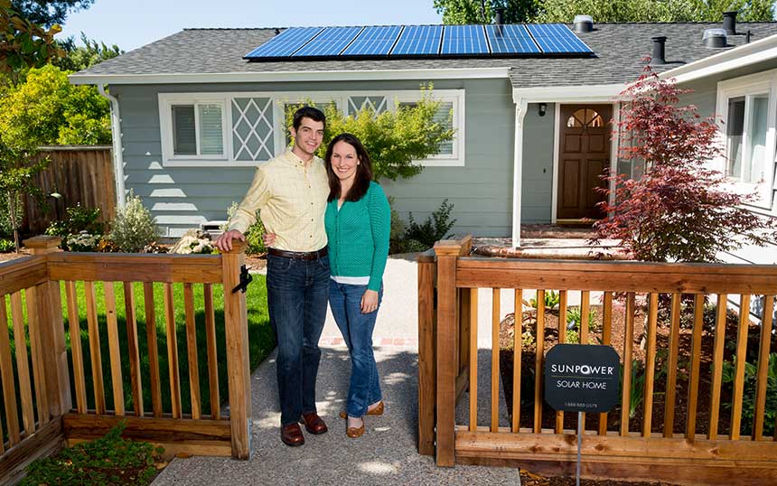 A happy couple is smiling in front of their home after going solar.